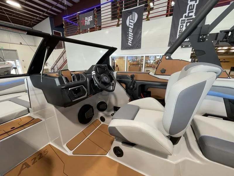 Slide: The Image of 2025 Axis A225 boat interior with modern dashboard and seating in showroom. - 15