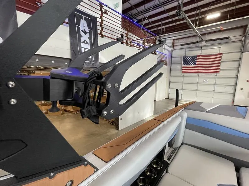 Slide: The Image of Axis A225 2025 boat interior with wakeboard rack and American flag in a showroom. - 22