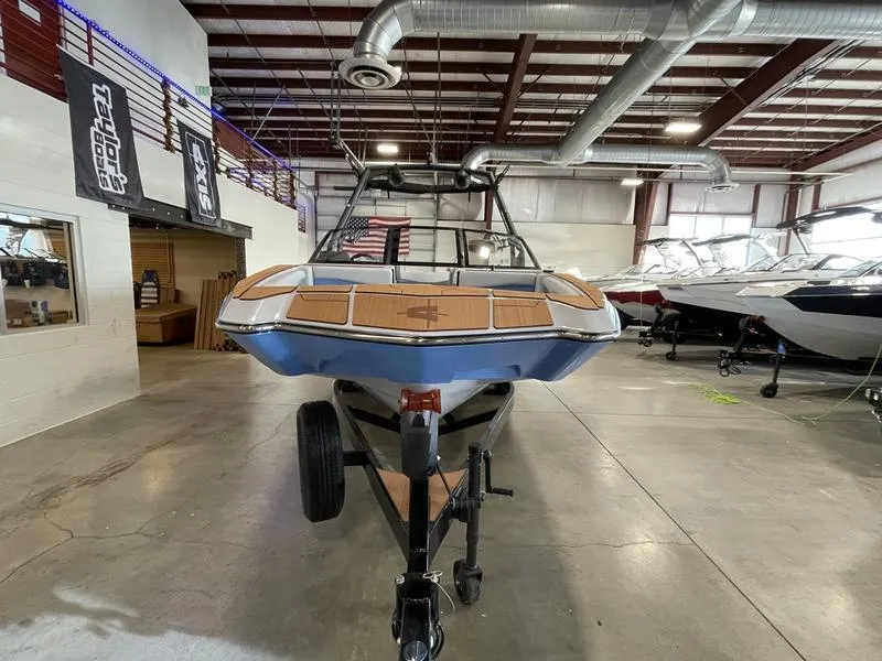 Slide: The Image of 2025 Axis A225 boat in showroom, front view, on trailer, industrial setting. - 4