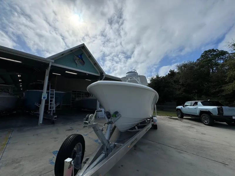 Slide: The Image of 2024 Front Runner 26 Center Console boat on trailer outside a garage under cloudy sky. - 6