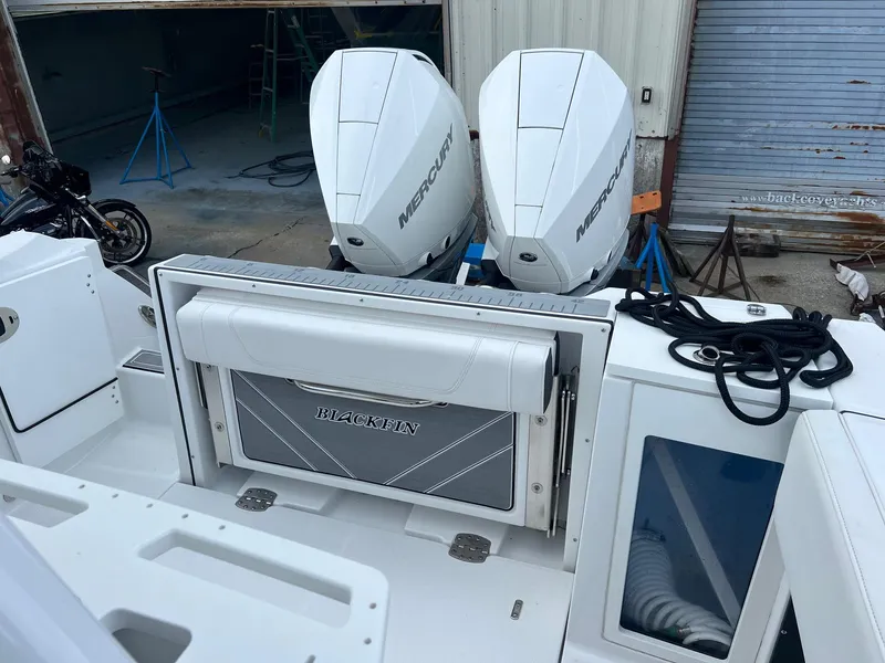 Slide: The Image of 2023 Blackfin 272 CC boat with dual Mercury engines, docked in a marina. - 10