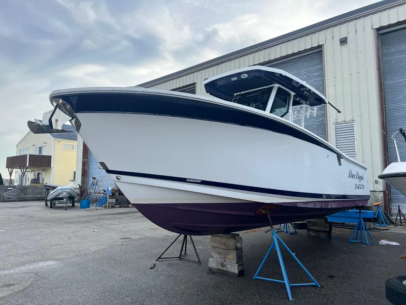 Slide: The Image of 2023 Blackfin 272 CC boat on stands, outside a warehouse. - 2
