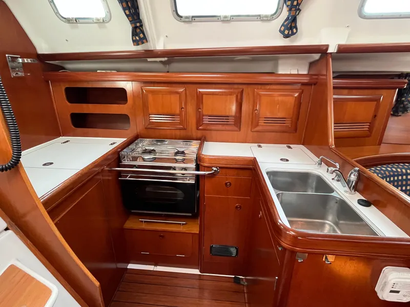 Slide: The Image of 2001 Beneteau Oceanis 393 yacht kitchen with wood cabinetry, stove, and dual sink. - 14