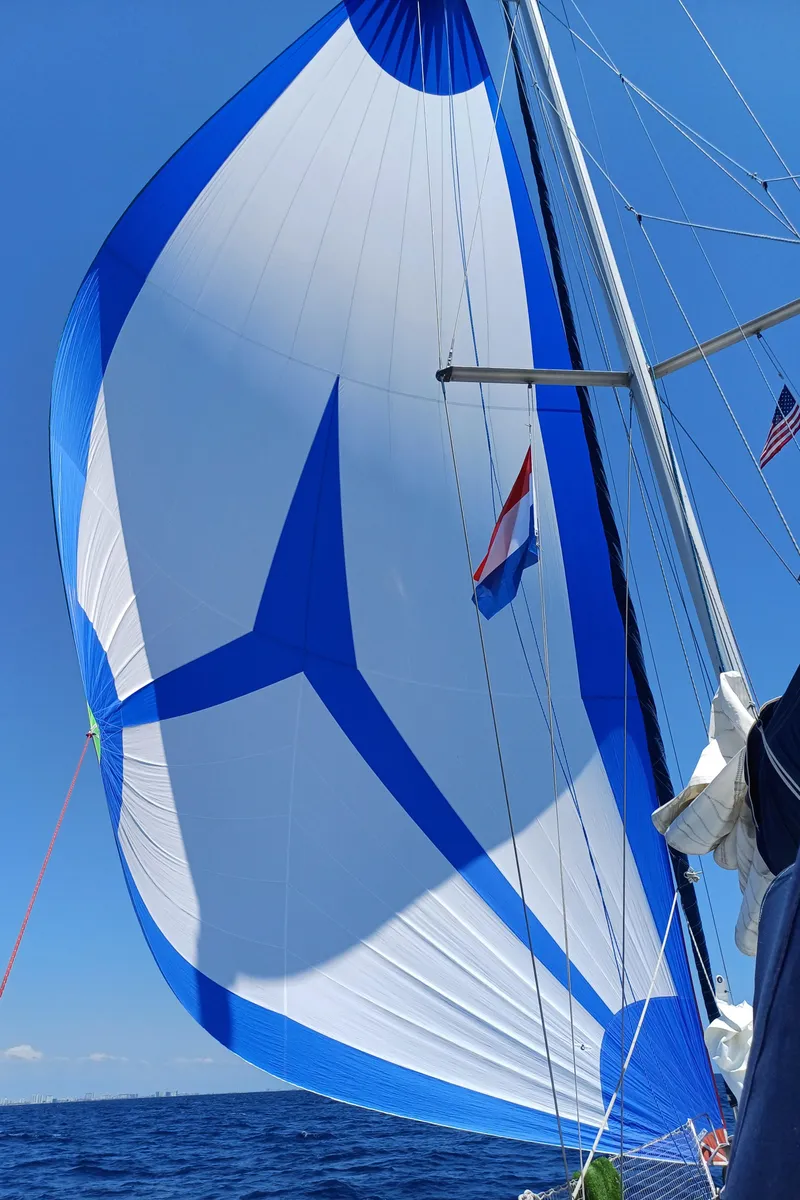 Slide: The Image of Sailing yacht Beneteau Oceanis 393 with blue and white spinnaker sail, 2001 model, on open sea. - 2