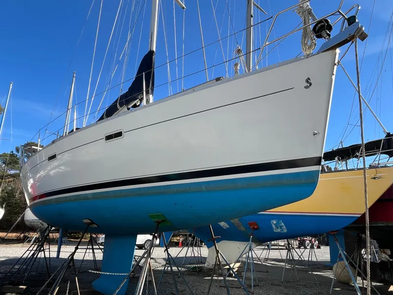Slide: The Image of 2001 Beneteau Oceanis 393 sailboat on stands, white hull, blue bottom, clear sky background. - 3