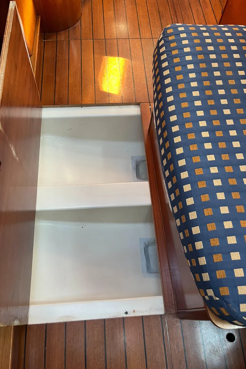 Slide: The Image of Beneteau Oceanis 393 (2001) interior storage compartment with patterned seating and wooden flooring. - 32