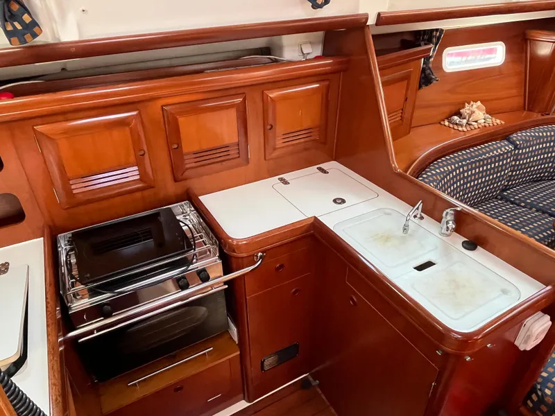 Slide: The Image of Interior of 2001 Beneteau Oceanis 393 yacht with wooden cabinetry and compact kitchen area. - 7