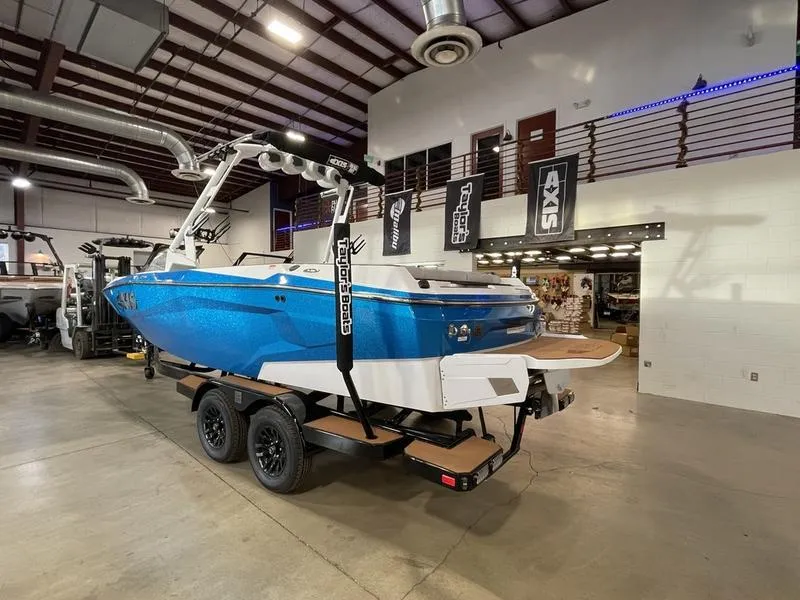 Slide: The Image of 2025 Axis A225 boat in showroom, blue exterior, on trailer, industrial setting. - 10