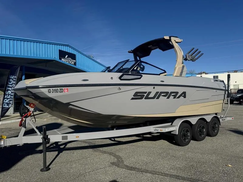Slide: The Image of 2025 Supra SE boat on trailer at dealership, sunny day. - 2