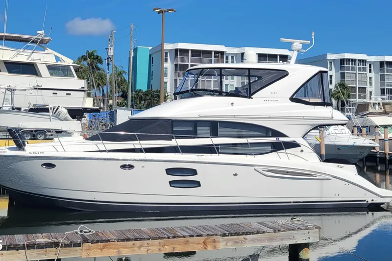Slide: The Image of 2011 Meridian 441 Sedan yacht docked at marina, with modern buildings in the background. - 67