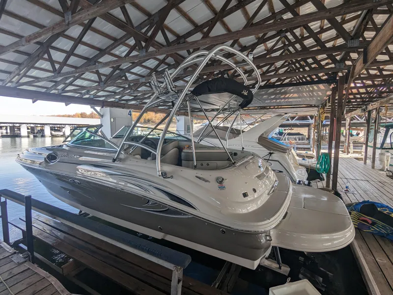 Slide: The Image of 2006 Sea Ray 240 Sundeck boat docked under a wooden canopy. - 12