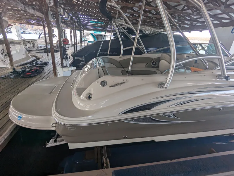 Slide: The Image of 2006 Sea Ray 240 Sundeck boat docked in a marina, featuring sleek design and spacious seating. - 15