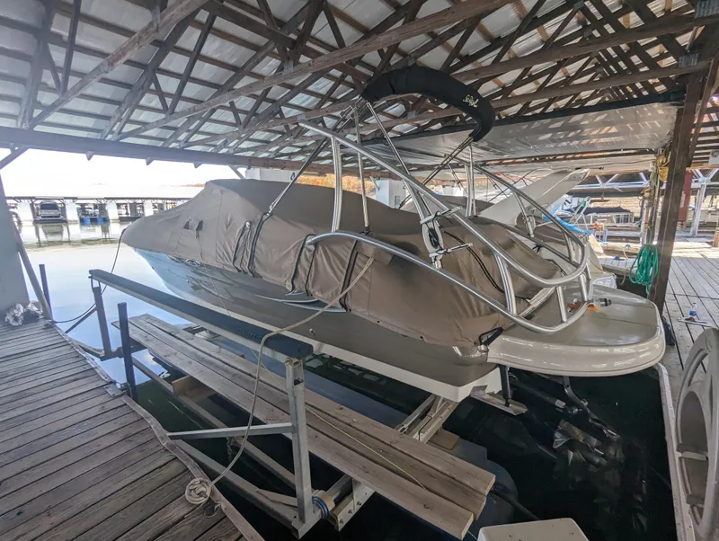 Slide: The Image of 2006 Sea Ray 240 Sundeck boat covered and docked in a marina. - 2
