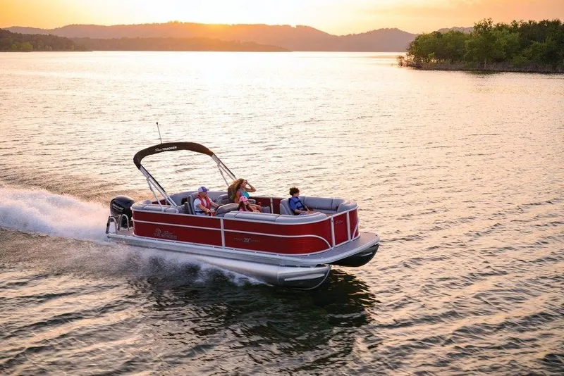 Slide: The Image of 2025 Sun Tracker Party Barge 22 DLX cruising on a serene lake at sunset. - 33