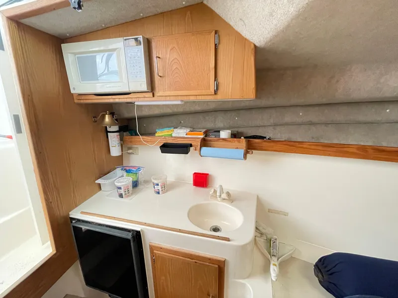 Slide: The Image of 1999 Henriques 28 Express boat interior with kitchenette, microwave, sink, and storage cabinets. - 16