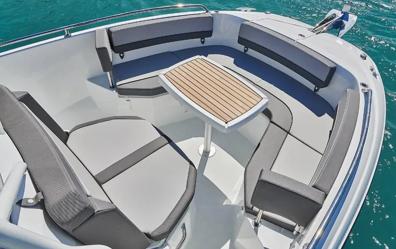 Slide: The Image of 2023 Jeanneau Leader 7.5CC S3 boat interior with seating and table on blue water. - 3