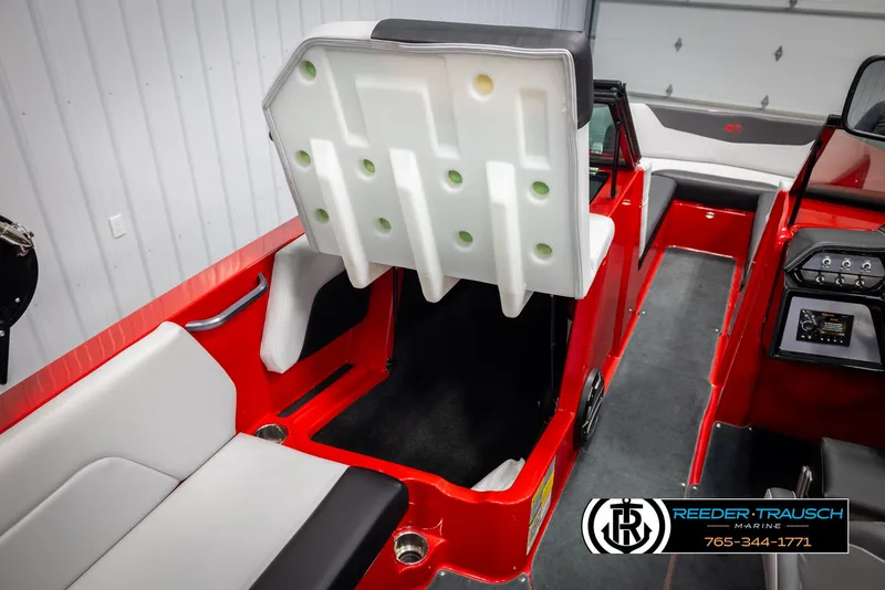 Slide: The Image of 2021 MasterCraft NXT24 interior with red and white seating, showcasing storage compartment. - 22