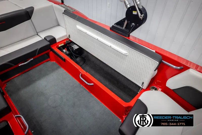 Slide: The Image of 2021 MasterCraft NXT24 boat interior with open storage compartment, red and gray seating. - 24