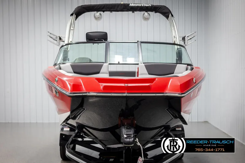Slide: The Image of 2021 MasterCraft NXT24 boat, red and black, displayed indoors at Reeder-Trausch Marine. - 8