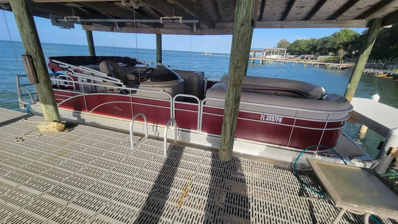 Slide: The Image of 2012 Bennington 2274 GL pontoon boat docked under a wooden canopy by the lake. - 0
