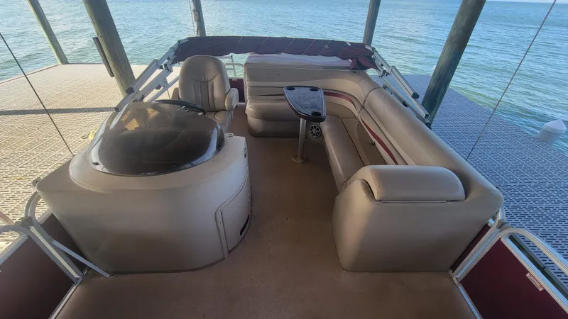 Slide: The Image of 2012 Bennington 2274 GL pontoon boat interior with seating and table, docked by the water. - 8
