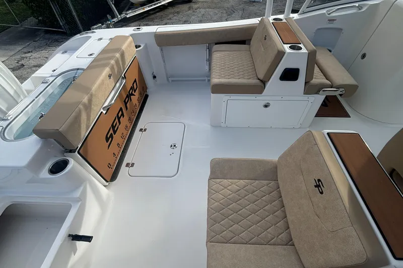 Slide: The Image of 2025 Sea Pro 240 Dual Console boat interior with beige seating and storage compartments. - 11
