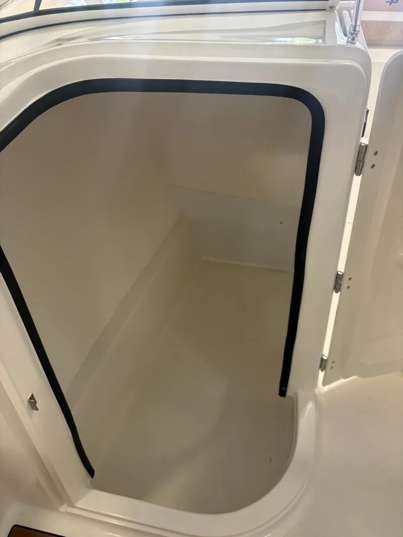 Slide: The Image of 2025 Sea Pro 240 Dual Console storage compartment with open door. - 12
