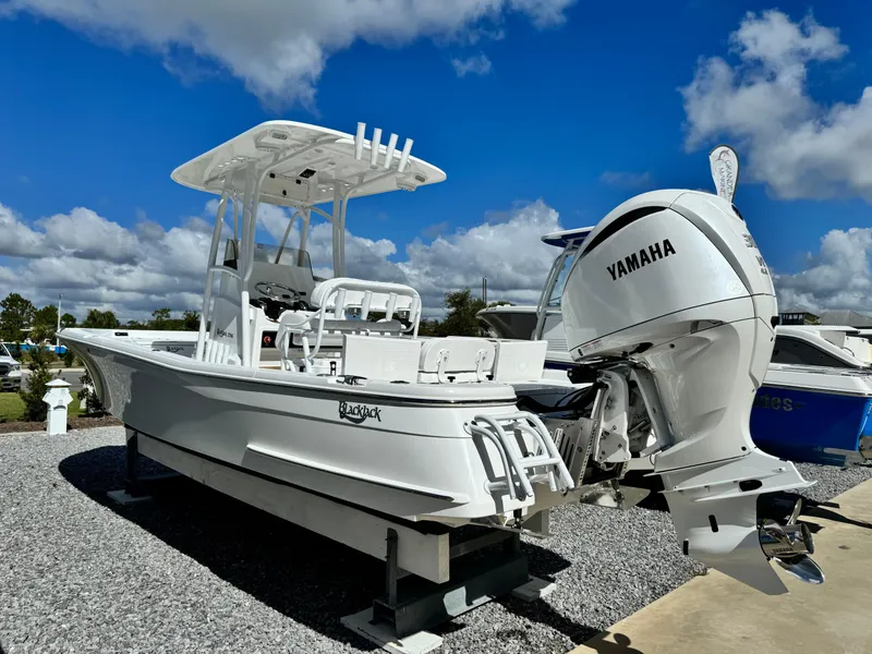 Slide: The Image of 2025 BlackJack 256 Bay boat with Yamaha engine, displayed outdoors on gravel. - 2