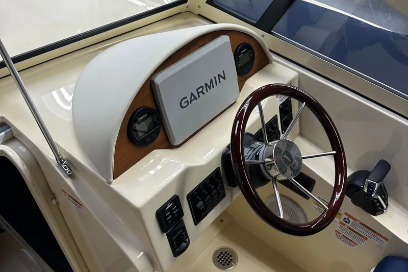 Slide: The Image of 2025 Rossiter 23 boat dashboard with Garmin navigation system and wooden steering wheel. - 6