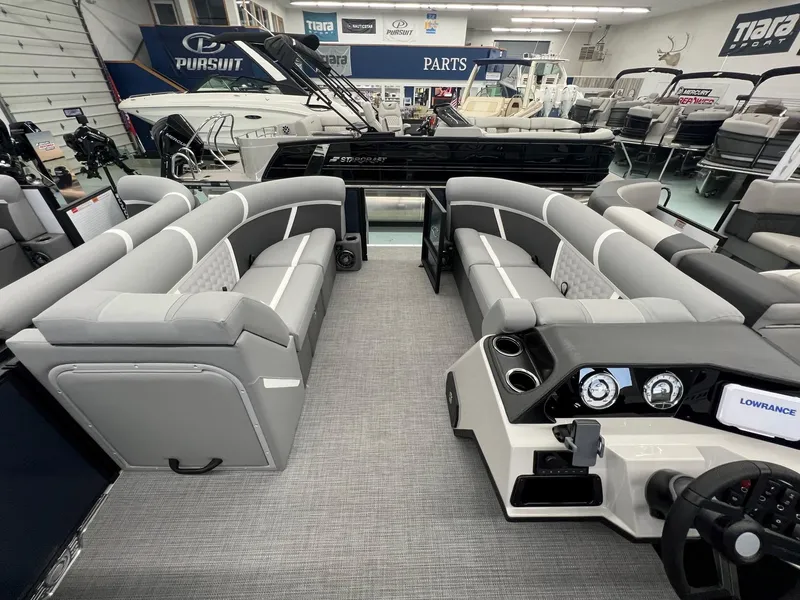 Slide: The Image of 2025 Crest Classic 220 pontoon boat interior with gray seating and modern dashboard in showroom. - 10