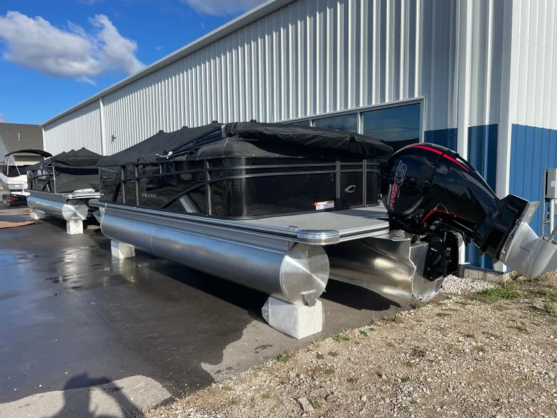 Slide: The Image of 2025 Crest CLASSIC 220 L pontoon boat with covered seating, parked outside a metal building. - 16