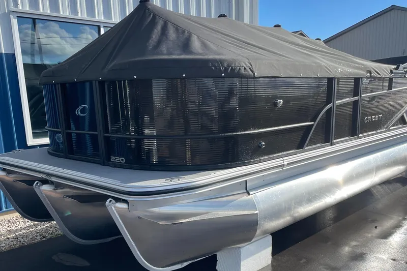 Slide: The Image of 2025 Crest CLASSIC 220 L pontoon boat with black cover, docked outdoors. - 20