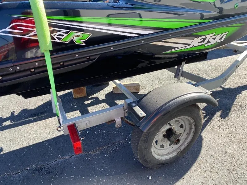 Slide: The Image of 2021 Kawasaki Jetski SX-R on trailer, black and green design, parked on asphalt. - 25