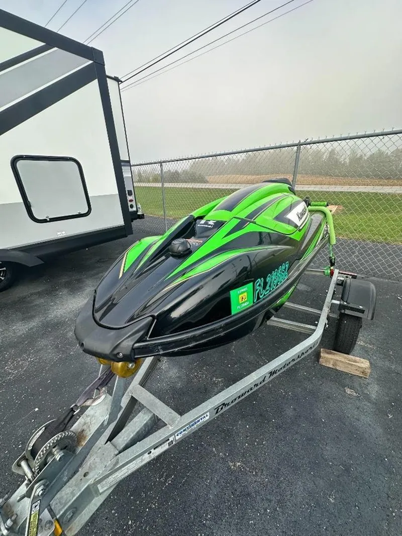 Slide: The Image of 2021 Kawasaki Jetski SX-R on trailer, black and green design, parked near fence. - 8
