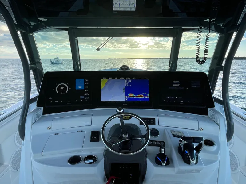 Slide: The Image of 2019 HCB 53 Sueños boat helm with advanced navigation screens at sunset. - 11