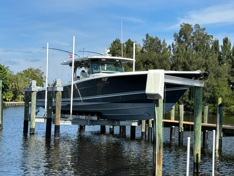 Slide: The Image of 2019 HCB 53 Sueños boat on lift, surrounded by water and trees. - 20
