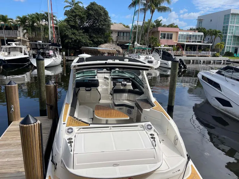 Slide: The Image of 2018 Sea Ray 350 SLX docked in a marina, surrounded by other boats and palm trees. - 26