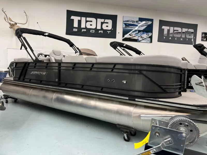 The Image of 2024 Starcraft SLS 5 Q DH pontoon boat in showroom, sleek design, Tiara Sport banners. - 1