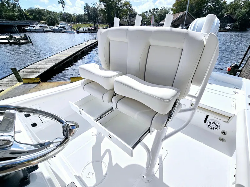 Slide: The Image of 2025 Sea Hunt BX 25 FS boat with white cushioned seats, docked by a serene waterfront. - 13