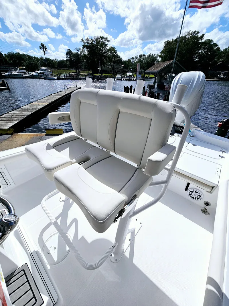 Slide: The Image of 2025 Sea Hunt BX 25 FS boat with white seating, docked by a scenic waterfront. - 14