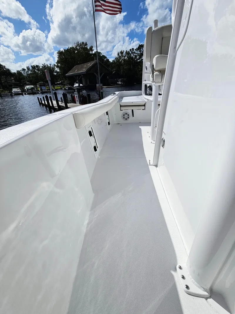 Slide: The Image of 2025 Sea Hunt BX 25 FS boat deck with American flag, docked by a lake. - 27