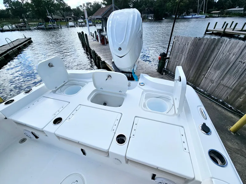 Slide: The Image of 2025 Sea Hunt BX 25 FS boat with open storage compartments, docked by a serene waterfront. - 9