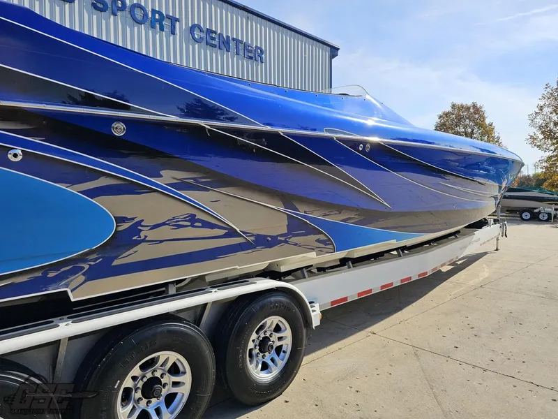 Slide: The Image of 2008 Outerlimits 46 Limited boat with sleek blue design on trailer at sport center. - 10