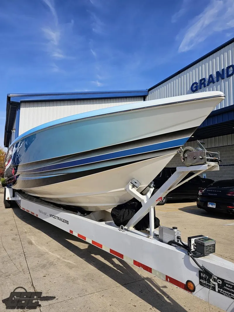 Slide: The Image of 2008 Outerlimits 46 Limited powerboat on trailer, parked outside a building under a clear sky. - 16