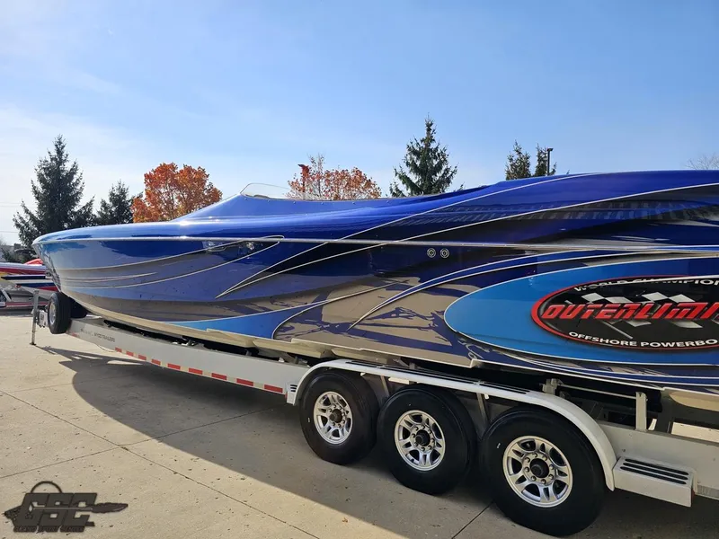 Slide: The Image of 2008 Outerlimits 46 Limited powerboat on trailer, vibrant blue design, parked outdoors. - 32