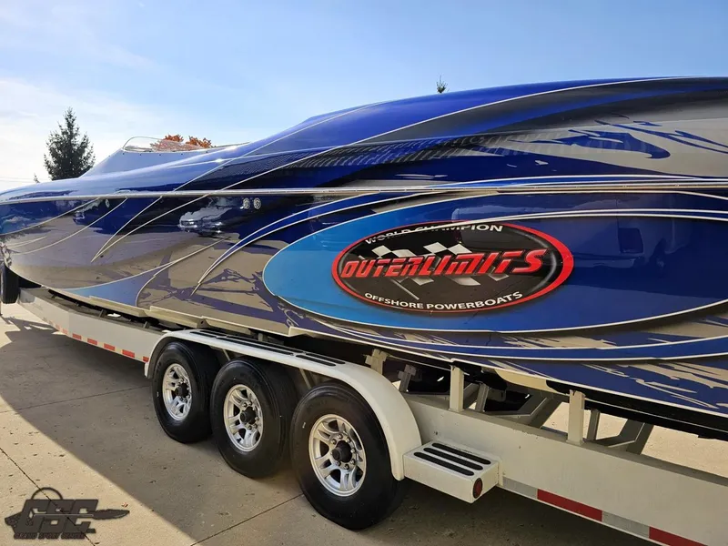 Slide: The Image of 2008 Outerlimits 46 Limited powerboat on trailer, featuring sleek blue design and logo. - 34