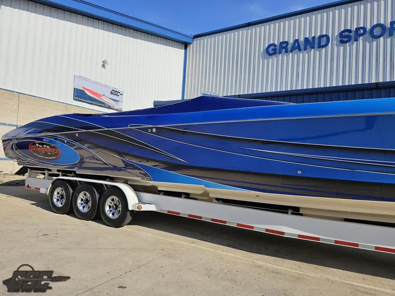 Slide: The Image of 2008 Outerlimits 46 Limited speedboat in blue, parked on a trailer outside a building. - 4