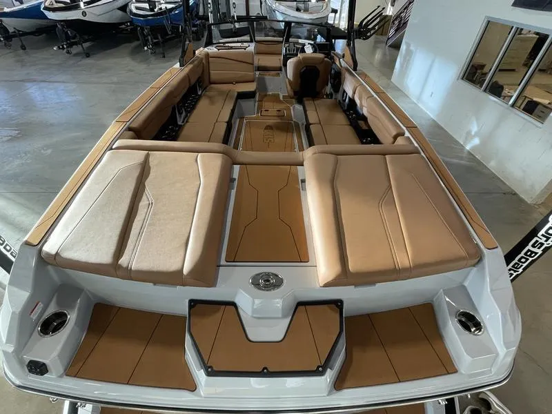Slide: The Image of 2025 Axis A245 boat interior with tan seating and sleek design in showroom. - 9