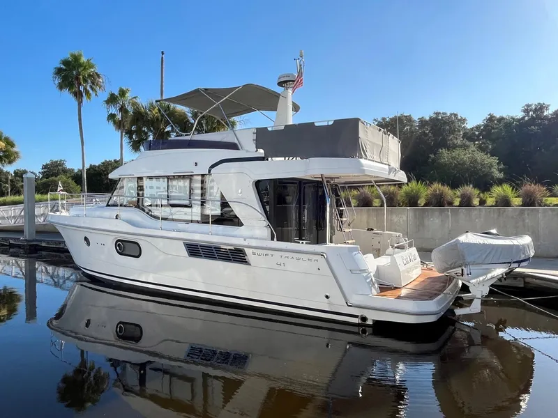 Slide: The Image of 2021 Beneteau Swift Trawler 41 docked, reflecting on calm water, with clear blue sky. - 3