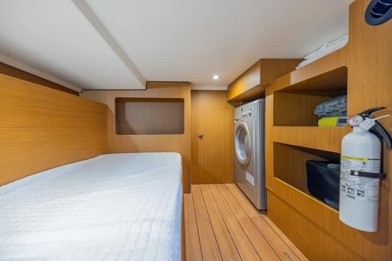 Slide: The Image of 2021 Beneteau Swift Trawler 41 cabin with bed, washing machine, and storage shelves. - 30